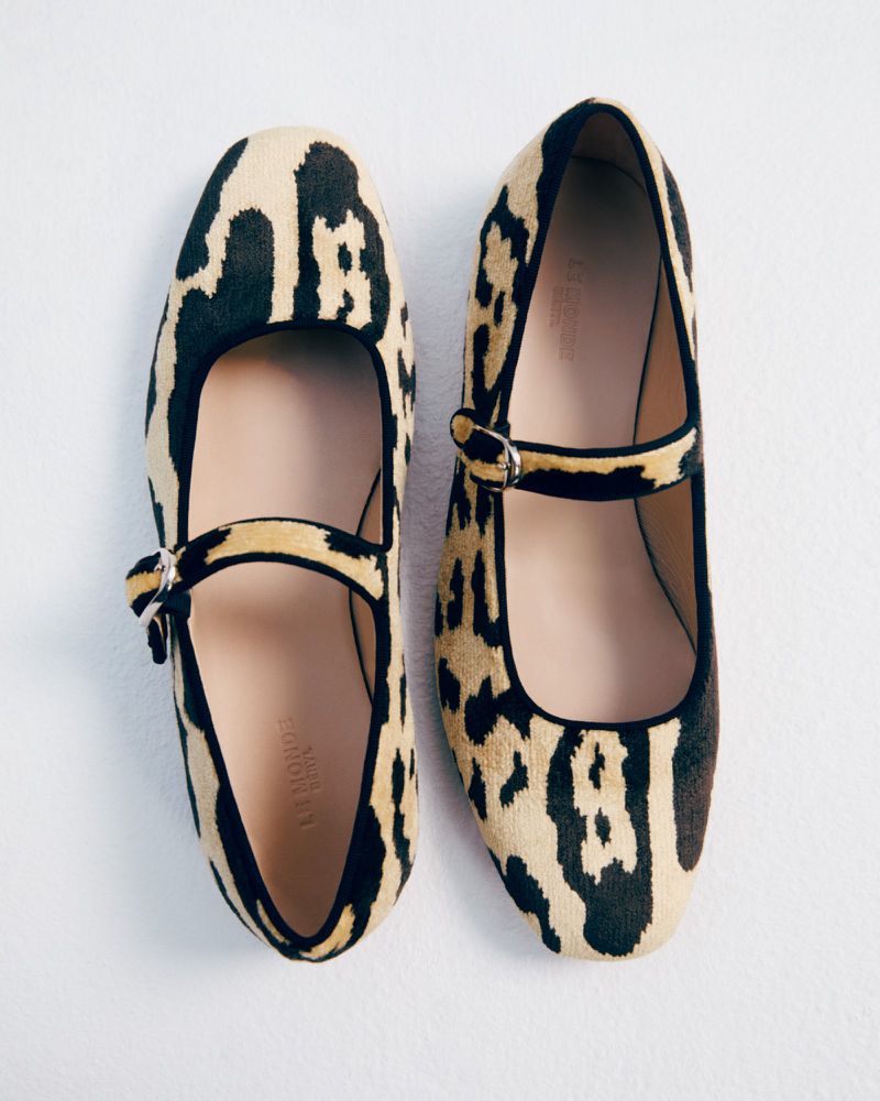 Leopard-print Mary Jane shoes. Close-up of two tan-and-black animal-print shoes with buckled straps on a white surface in portrait orientation.