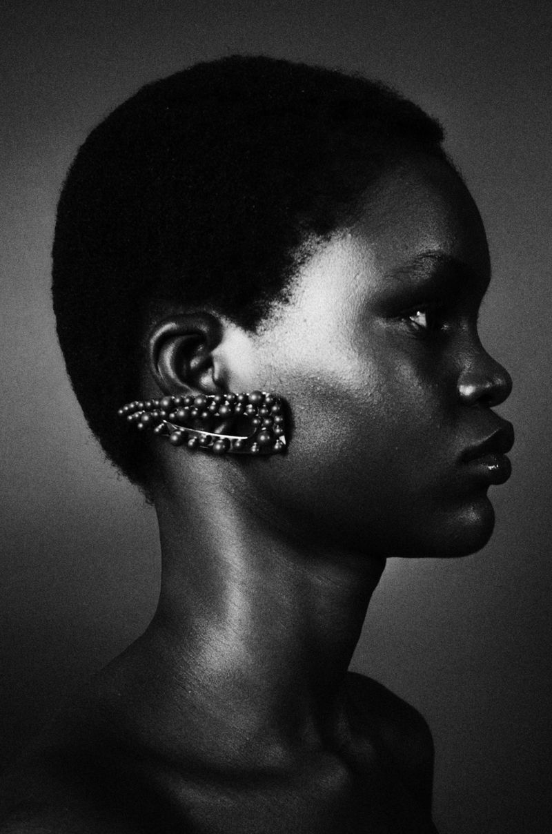 Black and white profile portrait of a Black model wearing a decorative embellished ear cuff.
