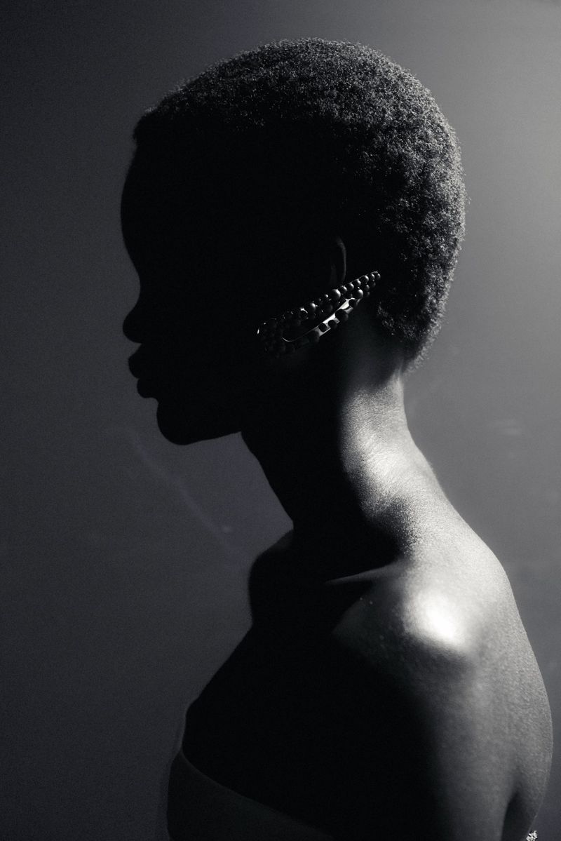 Black and white profile portrait of a model wearing a jeweled ear cuff under dramatic low-key lighting