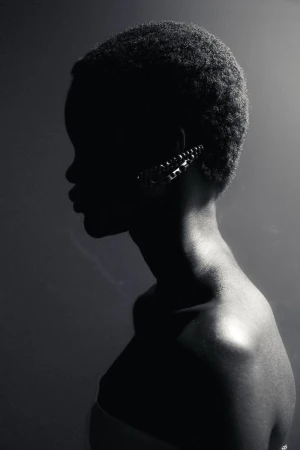Black and white profile portrait of a model wearing a jeweled ear cuff under dramatic low-key lighting