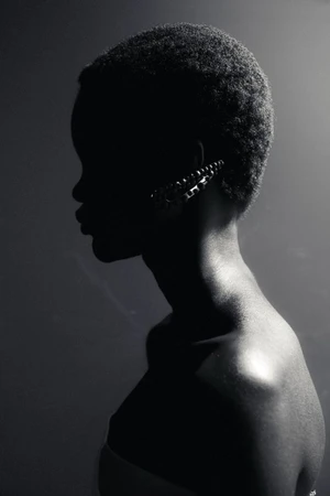 Black and white profile portrait of a model wearing a jeweled ear cuff under dramatic low-key lighting