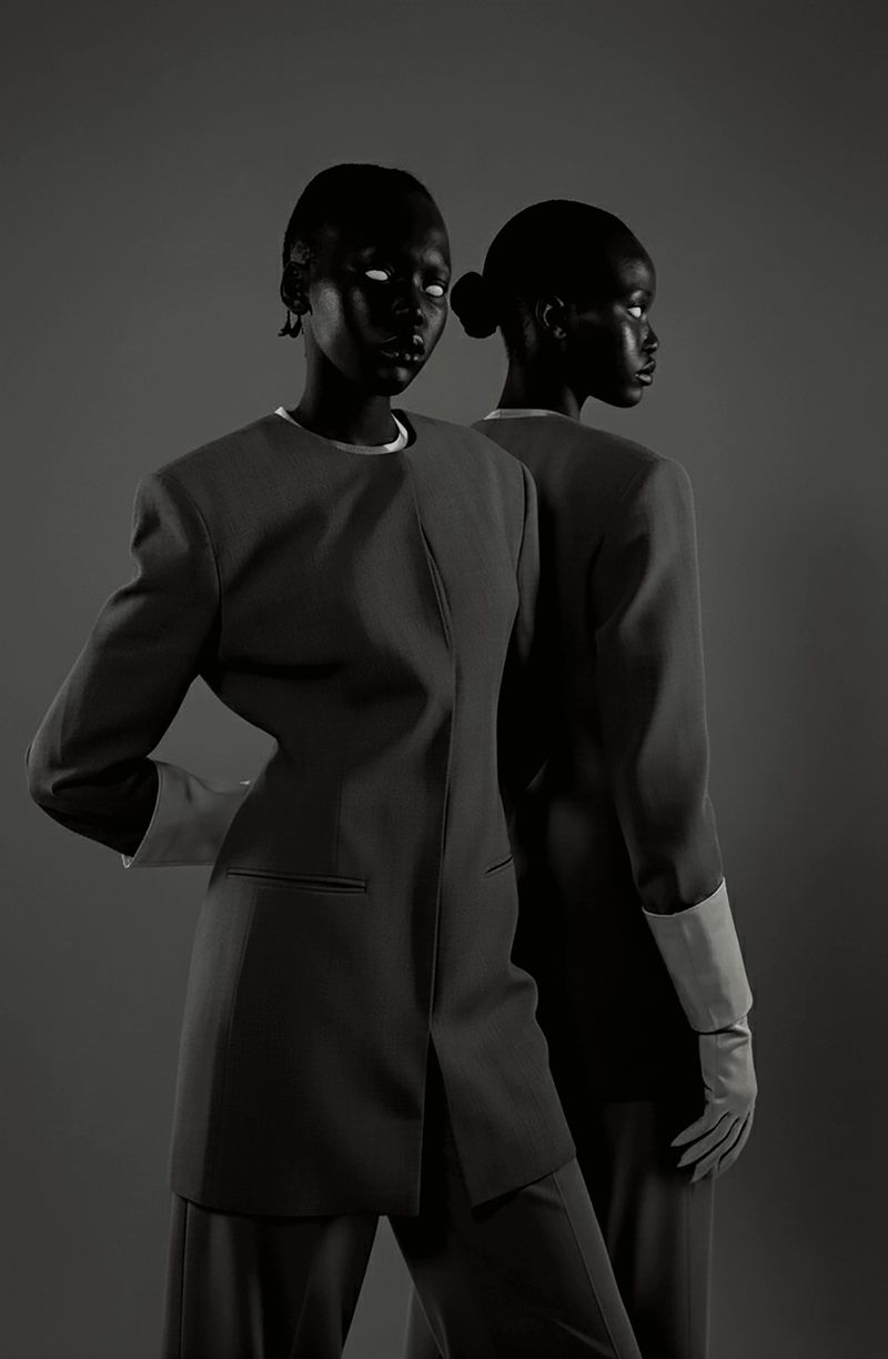 Two African adult females in a formal studio portrait. The women are wearing matching black suits, gloves, and slicked-back hair.