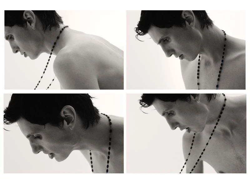 A monochrome collage of a shirtless person with short dark hair looking down while wearing a rosary necklace in a bright studio.