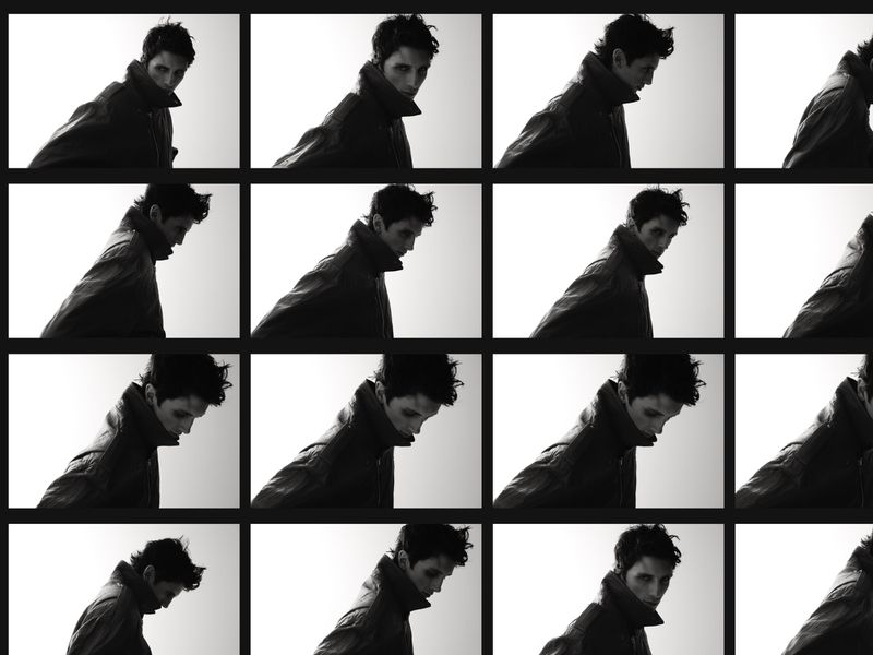 Monochromatic grid of a man in a jacket, facing slightly downward, repeated multiple times against a light background in a studio setting.