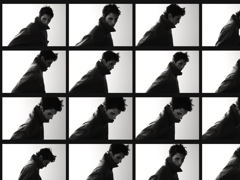 Monochromatic grid of a man in a jacket, facing slightly downward, repeated multiple times against a light background in a studio setting.