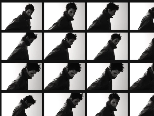 Monochromatic grid of a man in a jacket, facing slightly downward, repeated multiple times against a light background in a studio setting.