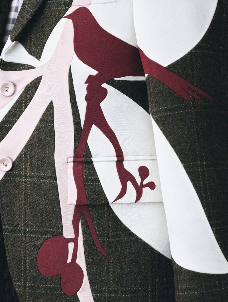 Close-up of a patterned blazer with a bird perched on a branch design, showcasing a blend of olive green, burgundy, white and light pink.