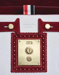 Close-up of a white and red leather handbag with gold metal hardware and signature grosgrain ribbon loop