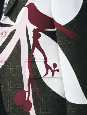 Close-up of a Thom Browne olive green plaid jacket featuring appliqué bird and branch motifs in burgundy and pink.
