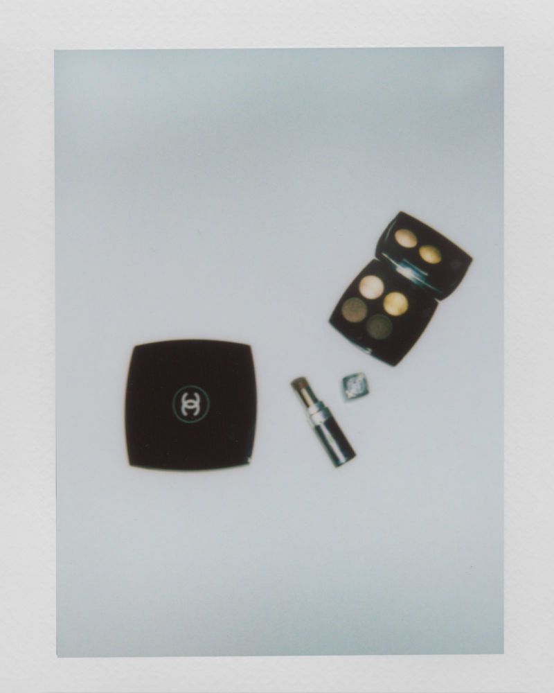 Overhead studio shot of Chanel makeup, including a compact, eyeshadow palettes, and lipstick on a white surface for beauty product photography.