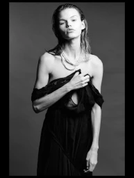 Model Daphne Maas wearing a dark gown and pearl necklace against a grey studio backdrop in a portrait by Oscar Ozbay.