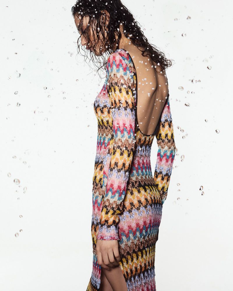 Model in a colourful patterned knit dress against a white background with floating water droplets