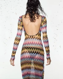 Model from behind wearing a colorful patterned long sleeve backless dress against a light background with water drops