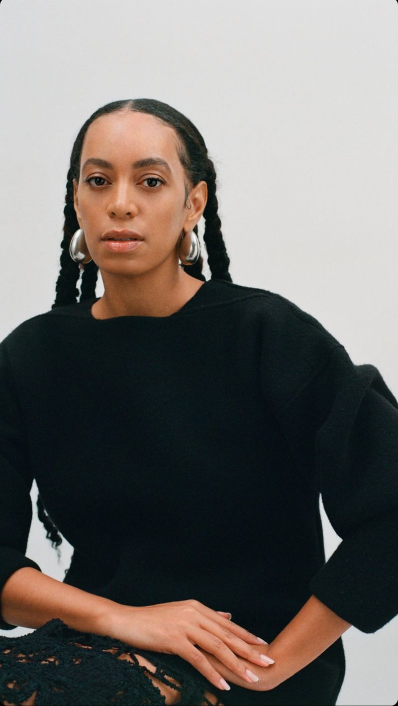 Solange Knowles wearing a black sweater and silver hoop earrings against a white background for Jil Sander.