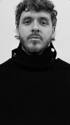 Monochrome portrait of Jack Harlow wearing a dark button-collared garment against a plain white studio background.