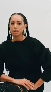 Solange Knowles wearing a black sweater and silver hoop earrings against a white background for Jil Sander.