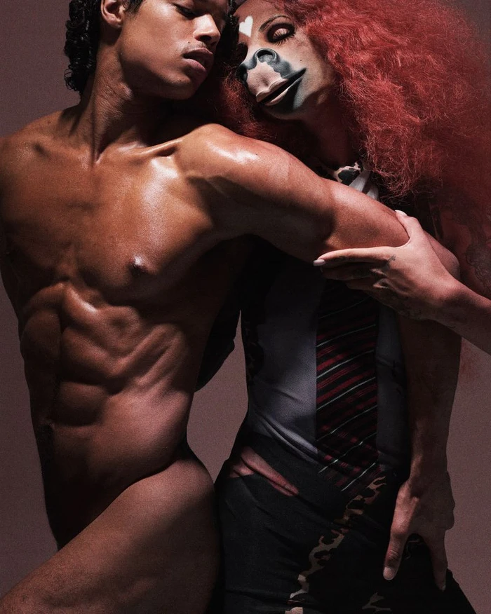 Shirtless male model posing next to a female model with voluminous red hair and artistic face makeup for Ottolinger.