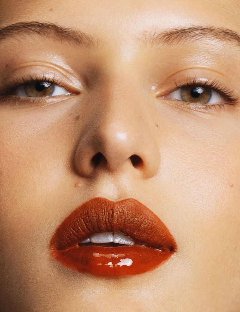 Close-up of a woman's face featuring vibrant red lips, defined eyebrows, and clear eyes, highlighting beauty and makeup artistry.