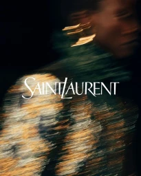 Motion blurred portrait of a model wearing a textured metallic patterned top with prominent gold earrings against a dark background.