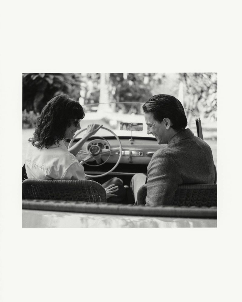 Black and white editorial image of a man and woman seated inside a classic convertible car for Tod's SS25 campaign.