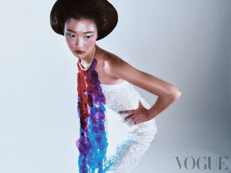Fashion editorial portrait of an Asian woman with stylized hair and makeup, wearing a white beaded dress and statement purple necklace.