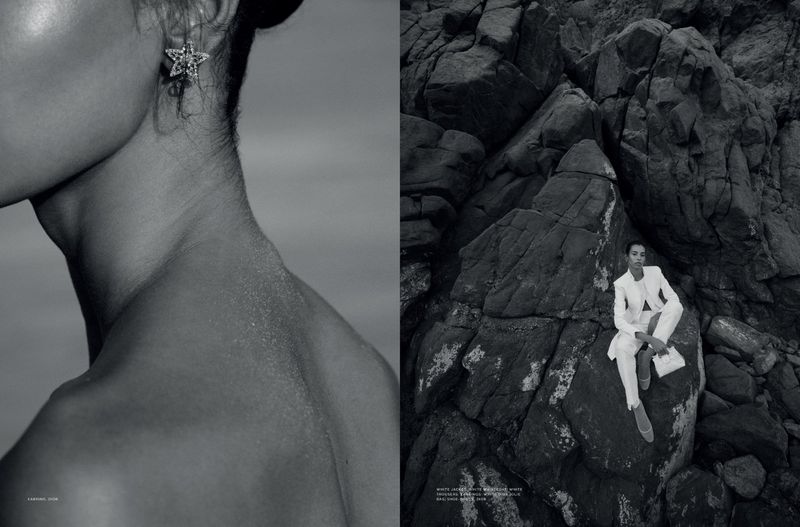 Monochrome fashion shot of a woman in a white suit sitting on rocks, with a close-up of a woman's neck and star earring.