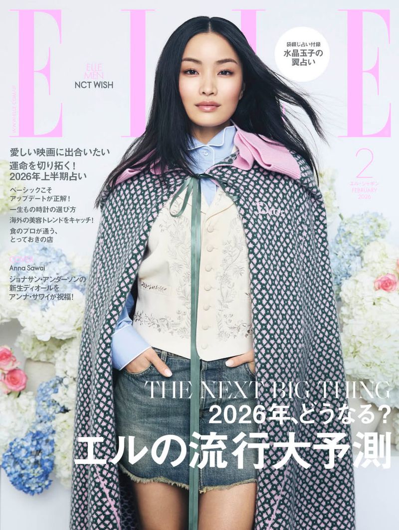 Magazine cover featuring Anna Sawai. She is wearing a cape, vest, and jean shorts, with floral arrangements in the background.