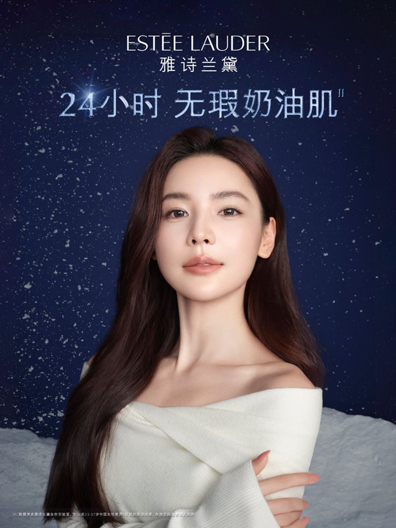Close-up studio shot of a woman in a white top against a blue starscape. Estée Lauder branding and Chinese text included.