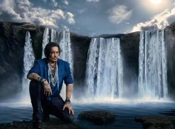 Johnny Depp kneeling in front of cascading waterfalls against a dramatic cloudy sky for Dior Sauvage Eau Forte.