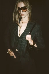 Model in pinstripe suit wearing large sunglasses and gold jewelry for Tom Ford Winter 24 campaign