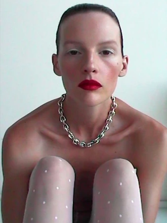 Model wearing a chunky silver chain necklace and white polka dot tights against a plain background