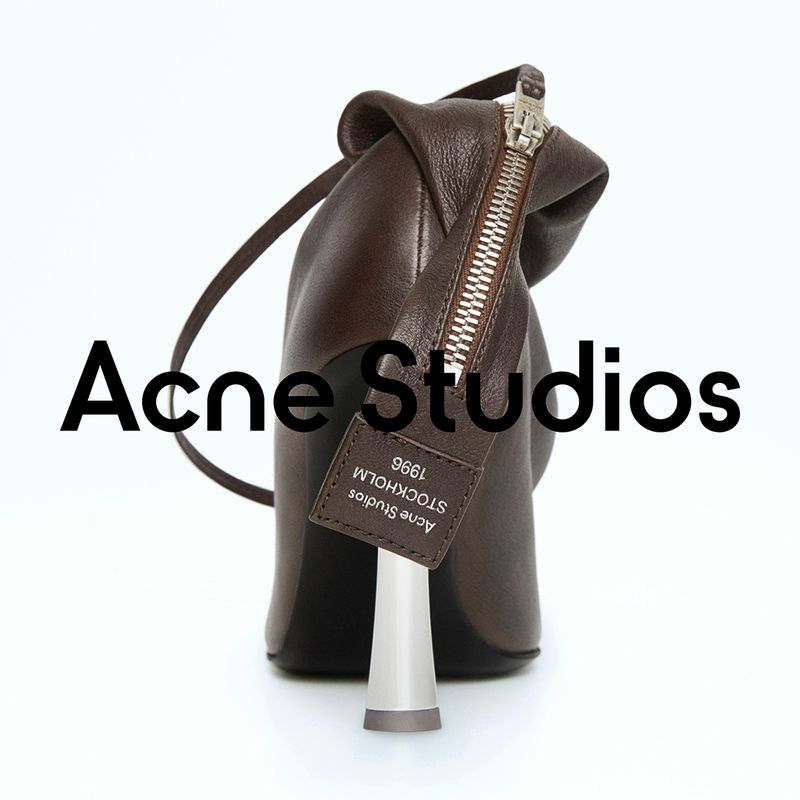 Studio shot of a brown leather ankle boot with a unique silver heel, featuring a zipper closure and Acne Studios logo tag on a white backdrop.