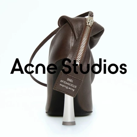 Studio shot of a brown leather ankle boot with a unique silver heel, featuring a zipper closure and Acne Studios logo tag on a white backdrop.