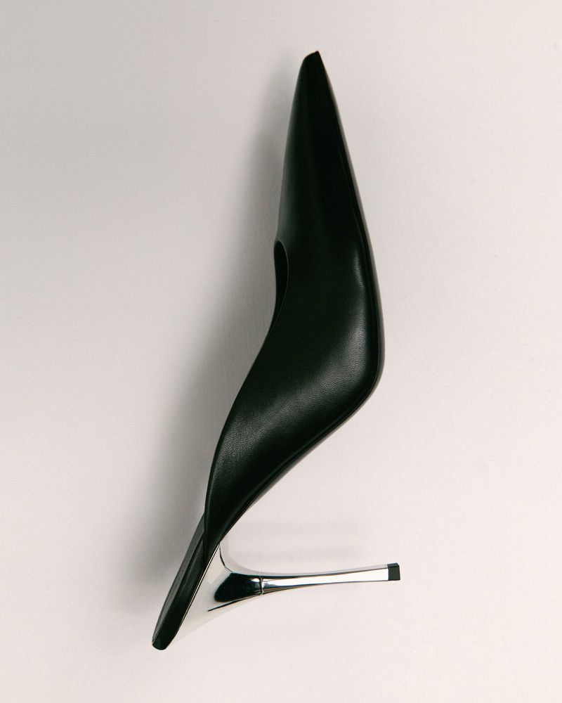 Isolated studio shot of a sleek black high-heel shoe with a metallic silver heel on a white background. Fashionable and elegant footwear.