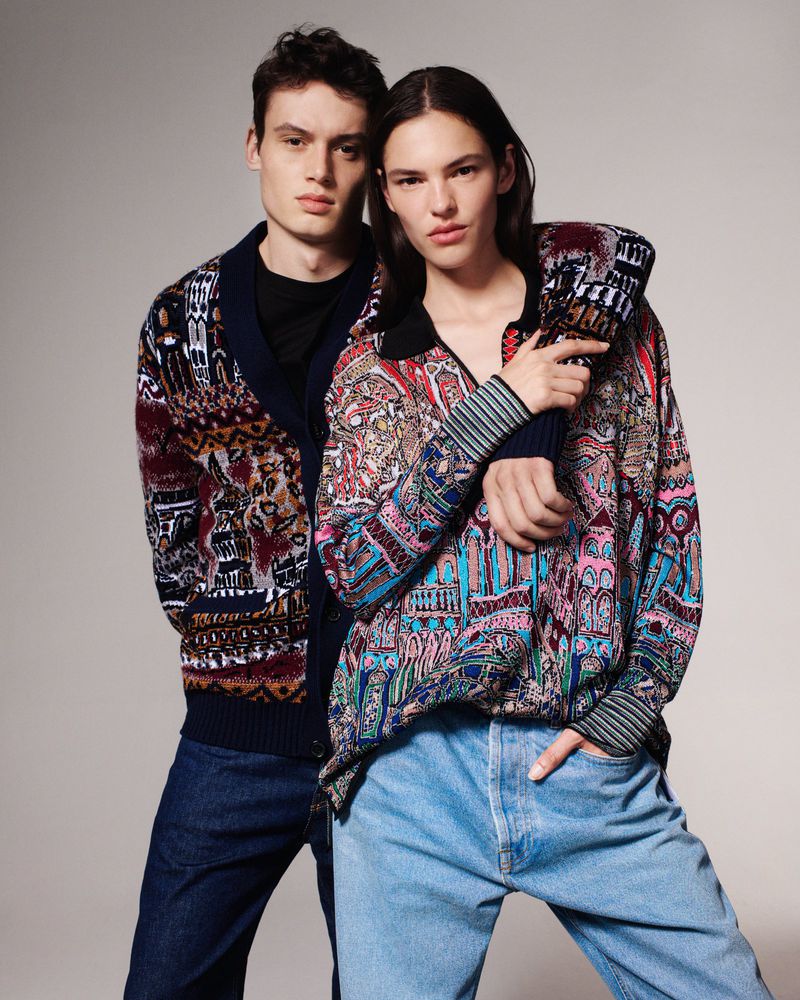 Two models posing against a neutral grey background wearing patterned knitwear and denim jeans for Missoni Fall Winter 2024.