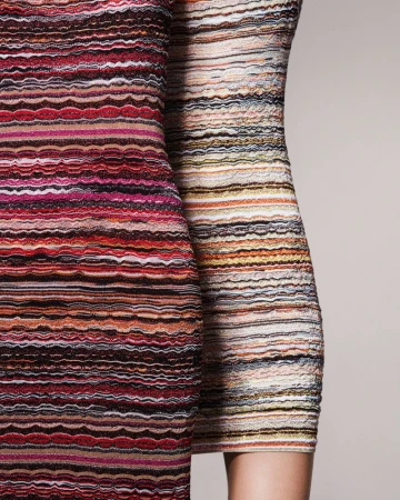 Close-up of two women wearing colorful striped dresses. Fashion photography showcasing dress patterns and design. Studio shot on a neutral background.