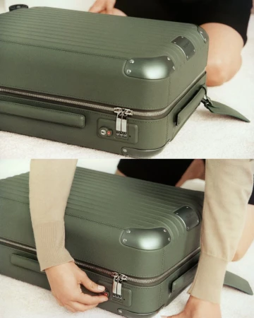 Close-up of a green suitcase with metal corner protectors and a combination lock, along with an adult interacting with the suitcase.