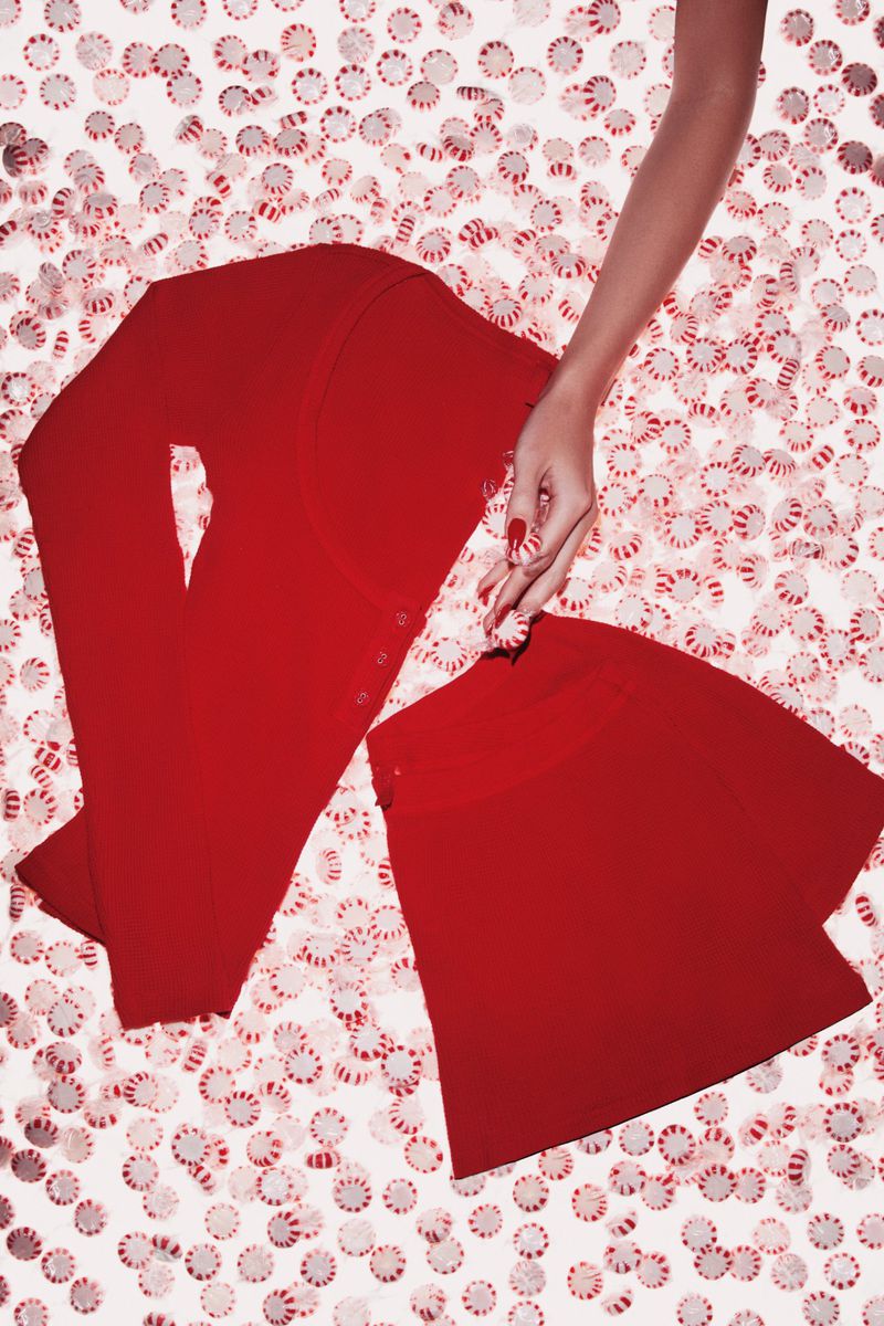 Overhead studio shot of red skirt and pants with a hand on a white background with red and white peppermint candies.