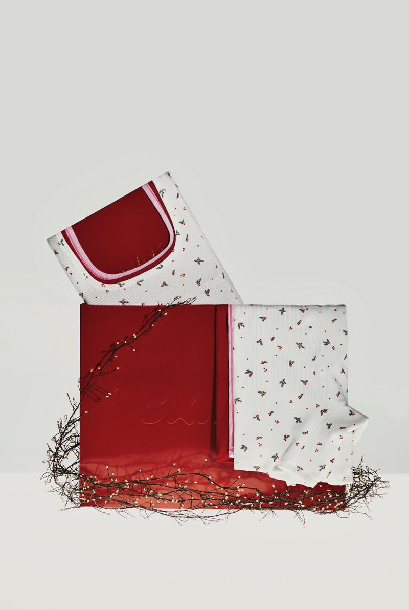 Red gift box set with patterned bedding and string lights. Bedding in the box has a white background and bird print pattern.