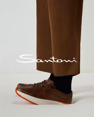 Santoni brown leather sneakers with white soles paired with brown cropped trousers on a white background.
