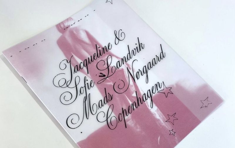 Fashion publication cover with an image of a figure and brand text in decorative fonts with star accents on a white surface.