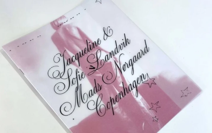 Fashion publication cover with an image of a figure and brand text in decorative fonts with star accents on a white surface.