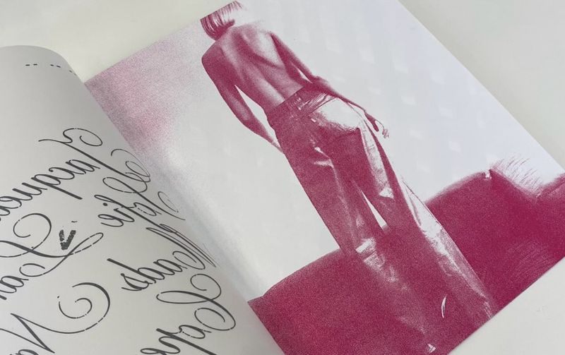 Fashion editorial featuring a model in wide-leg pants, showcased on a printed page with overlaid text in magenta and black ink.