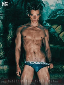 Shirtless male model wearing blue Bench/Body briefs posing in front of lush tropical vegetation on a calendar layout.