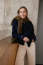 Model Karlina Caune wearing a navy cardigan and cream trousers against a concrete background for Simons Canada