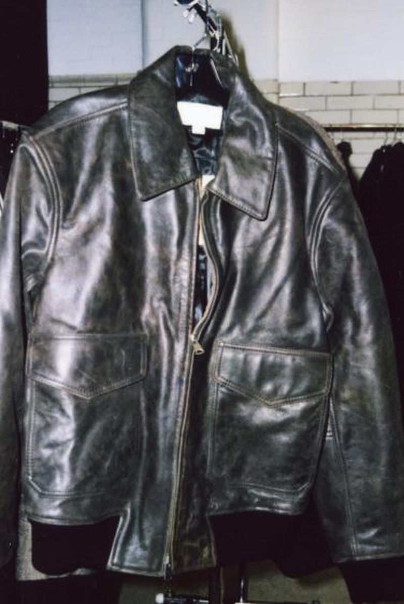 Dark brown leather jacket hanging on a rack, close-up view. Fashionable outerwear with pockets and a zip, suitable for editorial use.