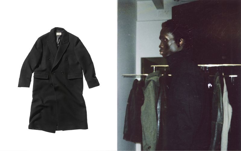 Black double-breasted overcoat on a white background next to an adult male with dark hair wearing black overcoat on rack.