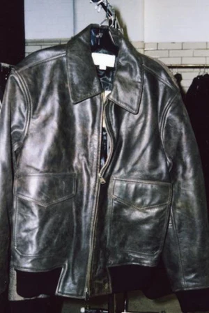 Distressed dark leather jacket hanging on a rack against a tiled wall for Zara Origins Fitting