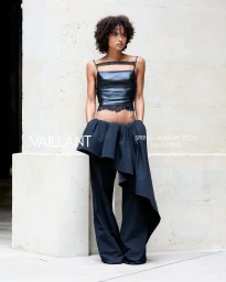 Model in black leather camisole and wide trousers posing against a stone architectural pillar for Vaillant