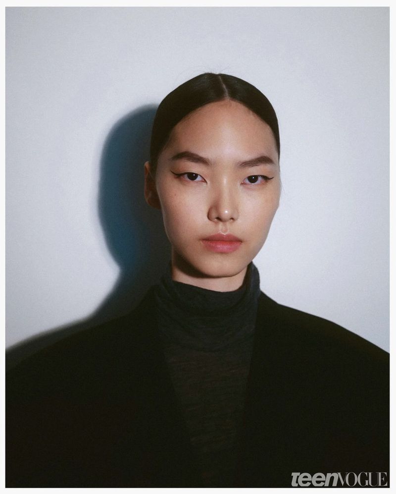 Asian woman with clean makeup and black top in a studio portrait for Teen Vogue, showcasing fashion and beauty photography.
